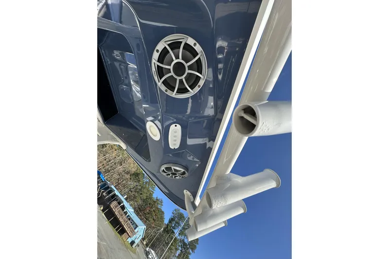 Slide: The Image of 2023 Yamaha Boats 252 FSH Sport, blue hull, speaker and rod holders, clear sky background. - 29