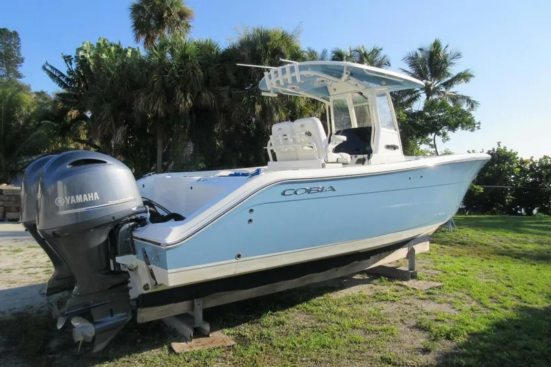 The Image of 2020 Cobia 280 Center Console boat with Yamaha engine, parked on grass. - 1