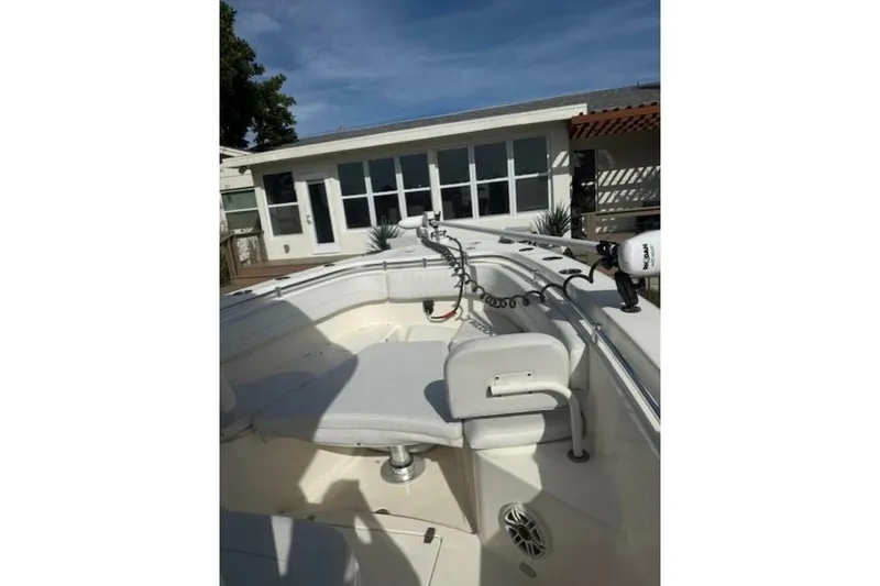 Slide: The Image of 2020 Cobia 280 Center Console boat interior with seating, docked near a modern house. - 4