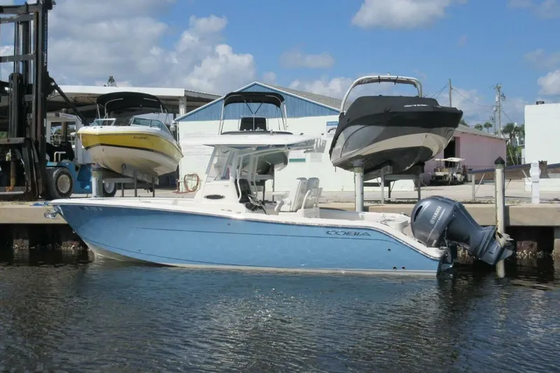 Slide: The Image of 2020 Cobia 280 Center Console boat docked at marina with other boats. - 8