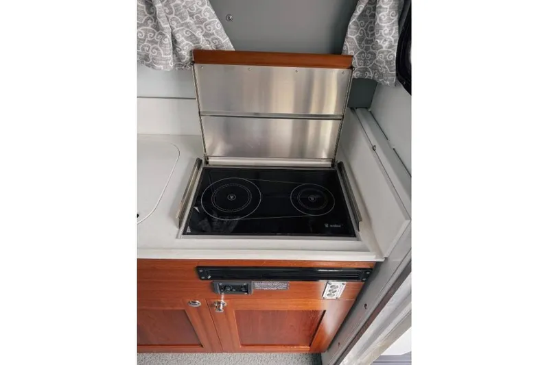 Slide: The Image of 2026 Hewescraft 290 Adventure kitchen with electric stove and wooden cabinetry. - 11