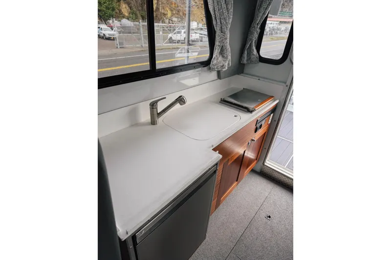 Slide: The Image of 2026 Hewescraft 290 Adventure boat interior kitchen with sink, countertop, and wooden cabinets. - 9