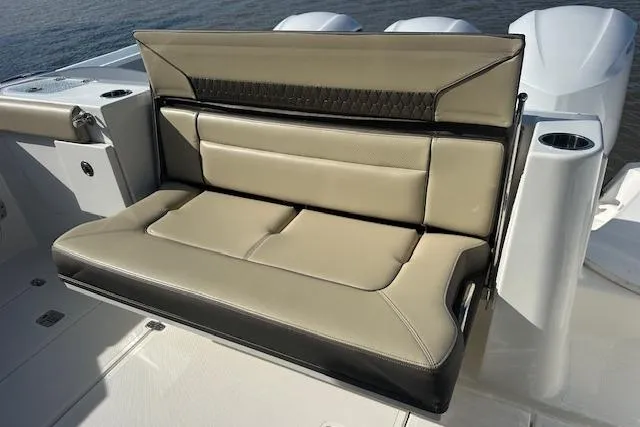 Slide: The Image of 2019 Pursuit DC 365 Dual Console boat seat, beige and black leather, on deck. - 14