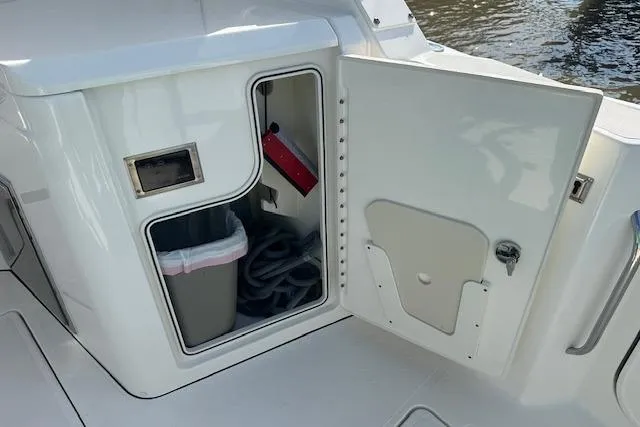 Slide: The Image of 2019 Pursuit DC 365 Dual Console storage compartment with trash bin and fire extinguisher. - 18