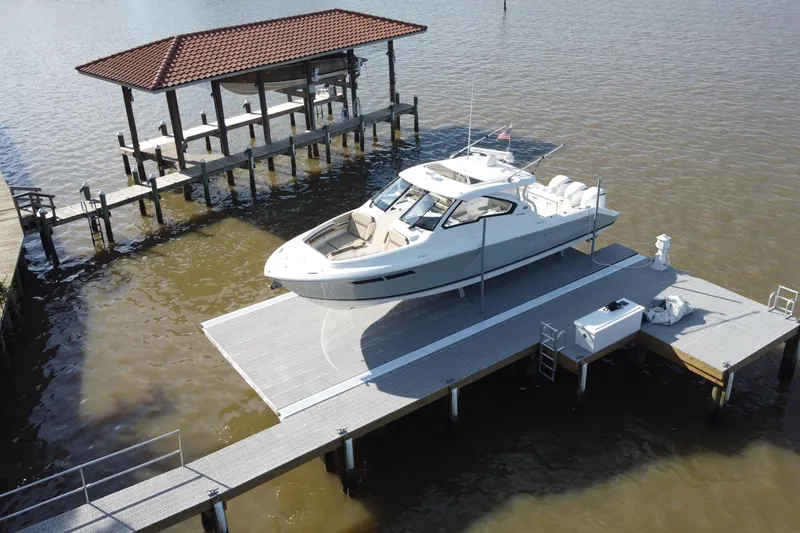Slide: The Image of 2019 Pursuit DC 365 Dual Console boat docked on a sunny waterfront pier. - 3