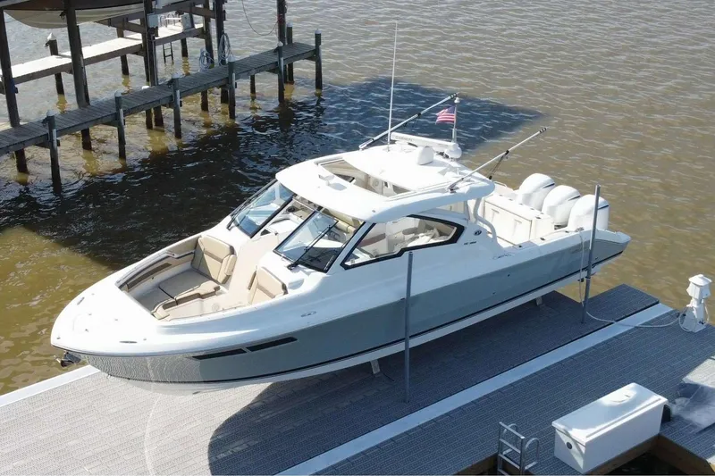 Slide: The Image of 2019 Pursuit DC 365 Dual Console boat docked by the water. - 4