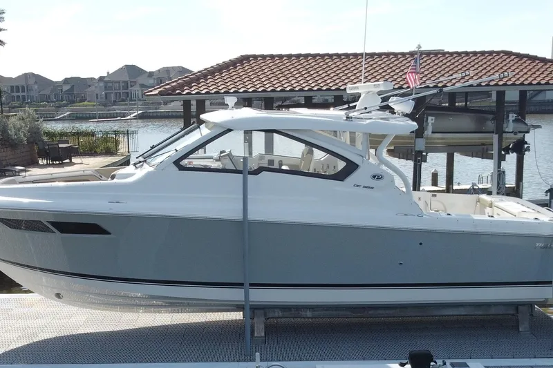 Slide: The Image of 2019 Pursuit DC 365 Dual Console boat docked by waterfront homes. - 8