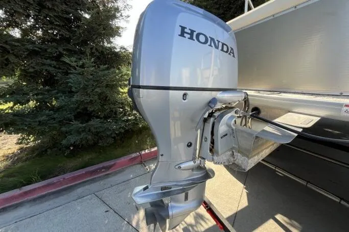 Slide: The Image of Silver Honda outboard motor attached to a 2013 Godfry Sweetwater boat, outdoors. - 17