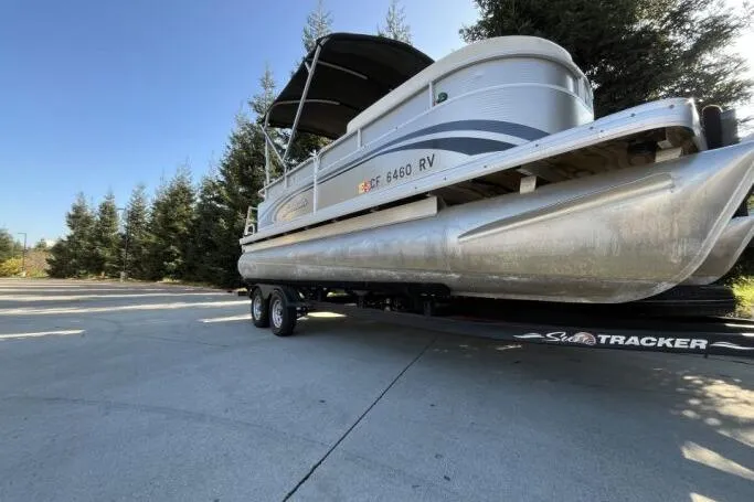 Slide: The Image of 2013 Godfry Sweetwater pontoon boat on trailer, parked near trees. - 19