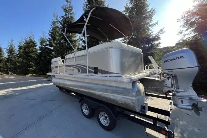Slide: The Image of 2013 Godfry Sweetwater pontoon boat with Honda motor on trailer, surrounded by trees. - 4