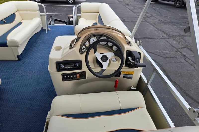 Slide: The Image of 2005 Odyssey 522C boat interior with steering console and seating, featuring blue carpet and beige upholstery. - 3