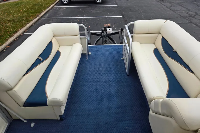Slide: The Image of 2005 Odyssey 522C boat interior with blue carpet and cream seating in a parking lot. - 7