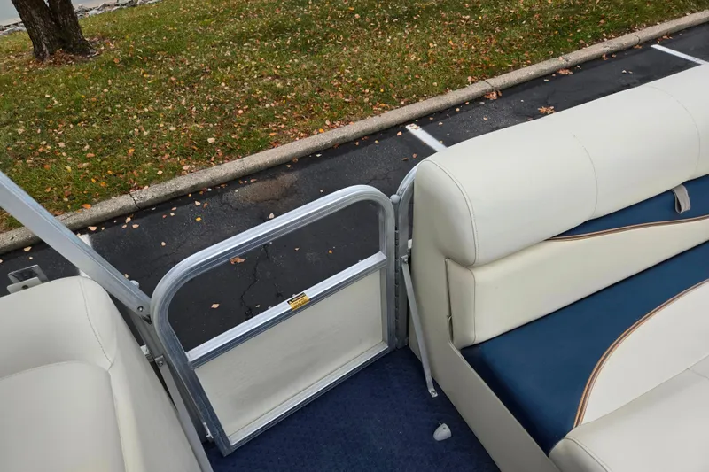 Slide: The Image of 2005 Odyssey 522C boat interior with white and blue seating, open gate, and autumn leaves. - 8