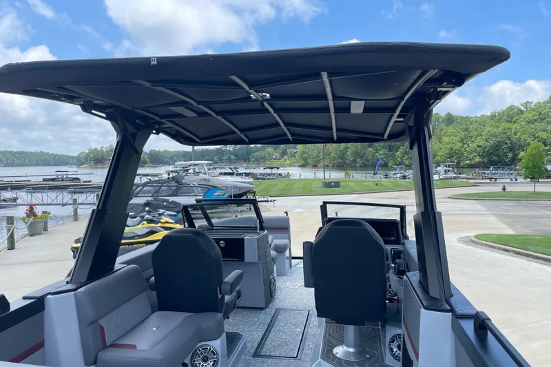 Slide: The Image of 2025 Revel RS25L boat interior with canopy, docked near a scenic marina. - 9