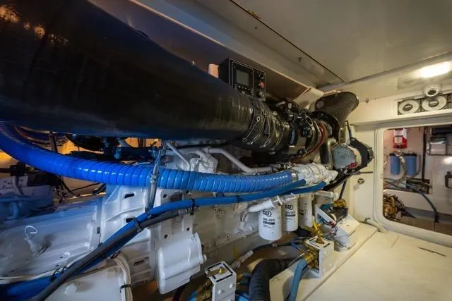 Slide: The Image of Engine room of a 1997 Garlington Convertible boat, showcasing complex machinery and blue hoses. - 59
