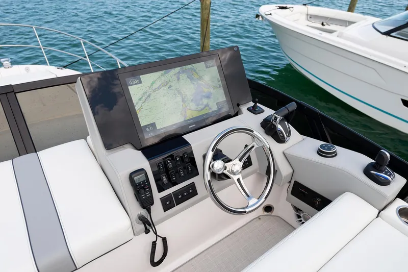 Slide: The Image of Manufacturer Provided Image: 2025 Regal 38 FXO helm with navigation display and steering wheel, docked by the water. - 105