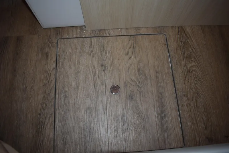 Slide: The Image of Wooden floor panel with a coin, inside a 2025 Regal 38 FXO boat. - 54