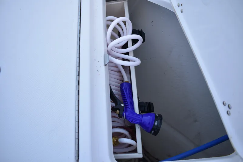 Slide: The Image of Storage compartment with coiled hose and spray nozzle on 2025 Regal 38 FXO boat. - 86