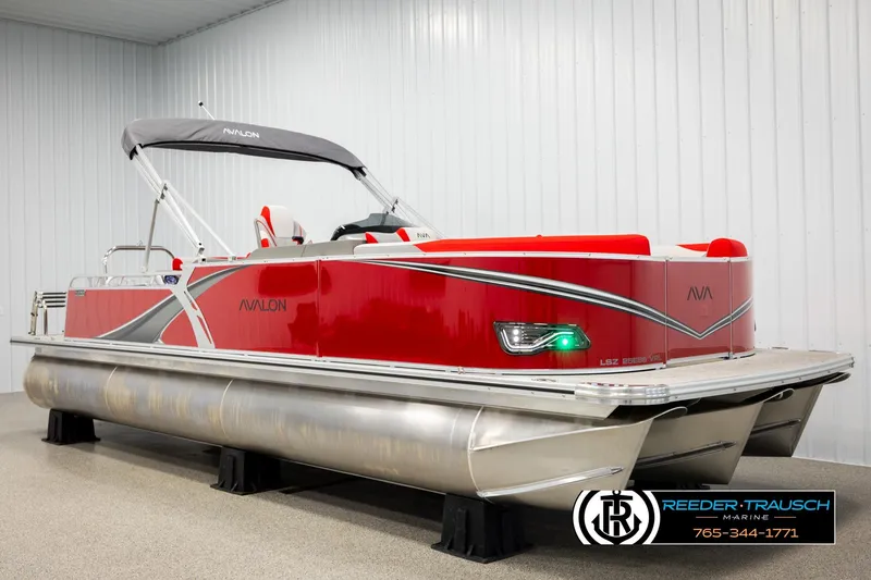 Slide: The Image of 2026 Avalon LSZ Vrl pontoon boat in showroom, featuring sleek red design and modern amenities. - 2