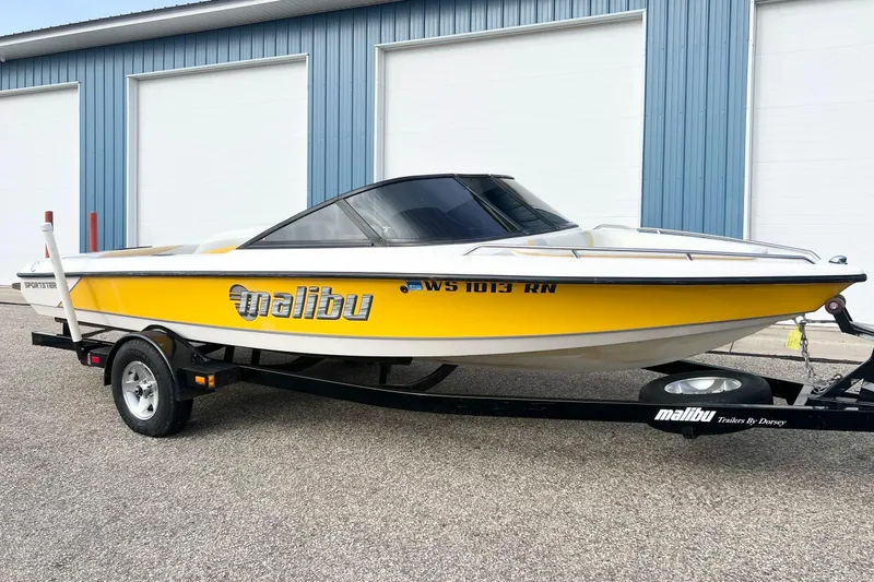 The Image of 2002 Malibu Sportster LX boat in yellow and white on a trailer, parked outside. - 0