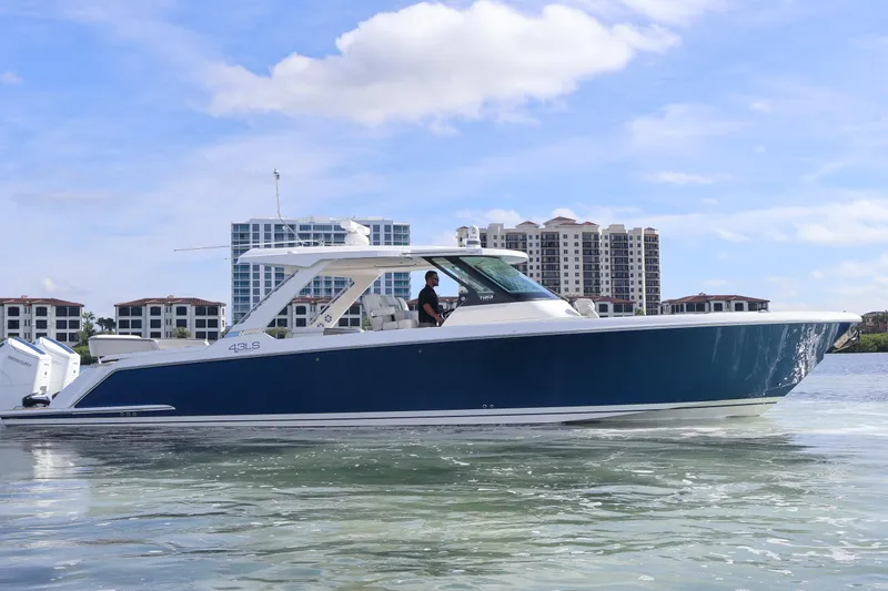 The Image of 2023 Tiara Yachts 43 LS luxury boat on water, with modern buildings in background. - 0