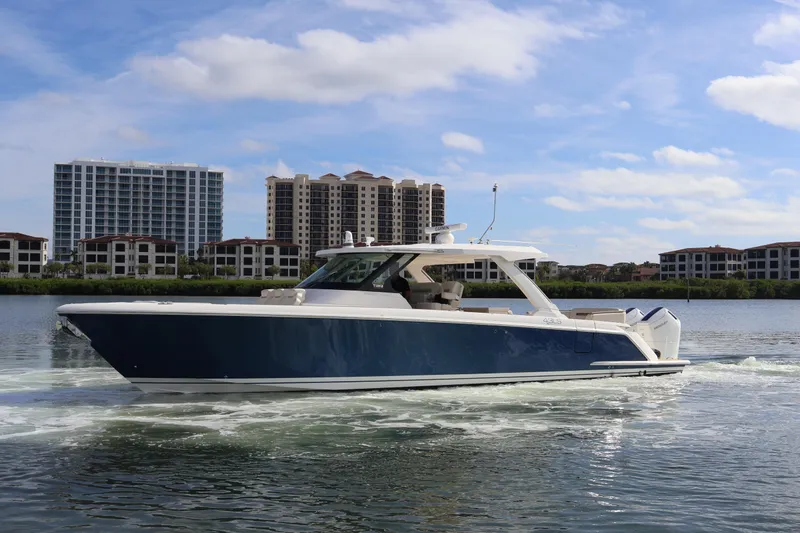 Slide: The Image of 2023 Tiara Yachts 43 LS cruising on water with cityscape background. - 10