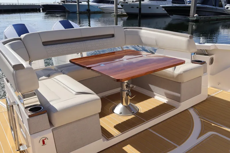 Slide: The Image of 2023 Tiara Yachts 43 LS luxury seating area with wooden table, docked at marina. - 17
