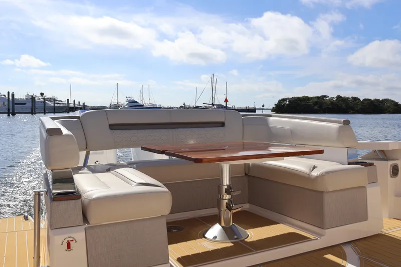 Slide: The Image of 2023 Tiara Yachts 43 LS luxury seating area with table, overlooking marina. - 19