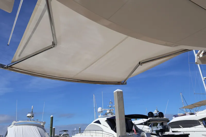 Slide: The Image of 2023 Tiara Yachts 43 LS with extended sunshade at marina, clear blue sky. - 20