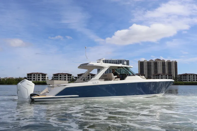 Slide: The Image of 2023 Tiara Yachts 43 LS cruising on water with modern buildings in background. - 4