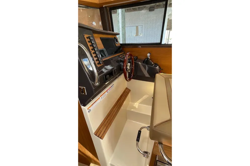 Slide: The Image of 2025 Ranger Tugs R-27 Seakeeper Ride helm with modern controls and wood accents. - 23