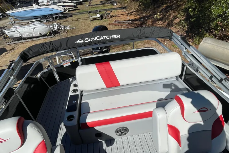 Slide: The Image of 2026 SunCatcher Select 322SL boat interior with gray and red seating, cup holders, and SunCatcher branding. - 17