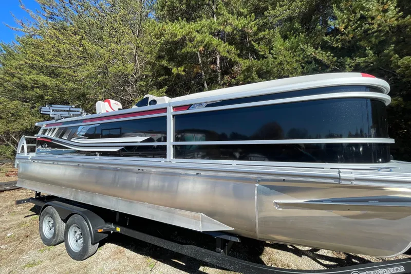 Slide: The Image of Manufacturer Provided Image: 2026 SunCatcher Select 322SL pontoon boat on a serene lake with passengers enjoying the view. - 24