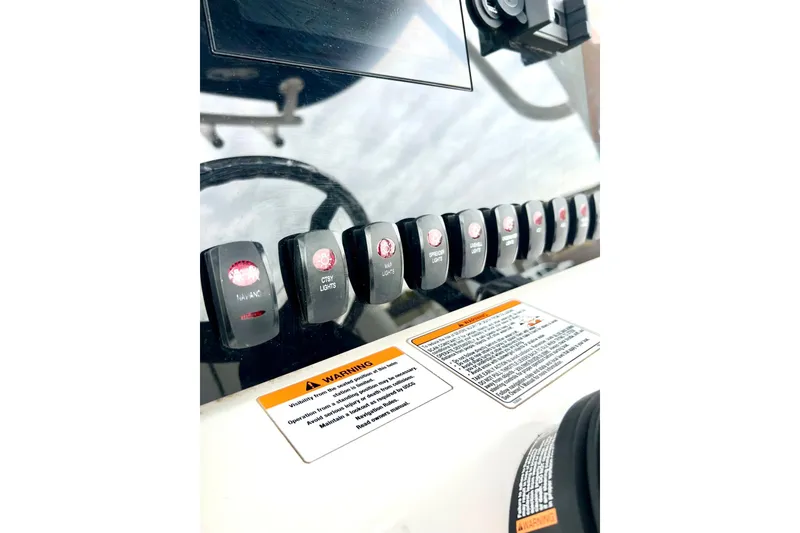 Slide: The Image of Control panel of 2022 Yamaha Boats 255 FSH Sport H with labeled switches and warning labels. - 39