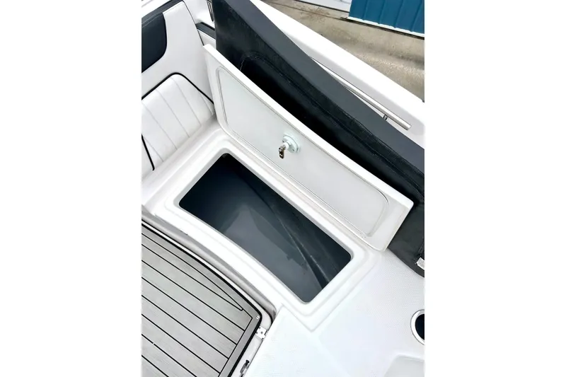 Slide: The Image of 2022 Yamaha Boats 255 FSH Sport H storage compartment, open lid, white interior. - 52