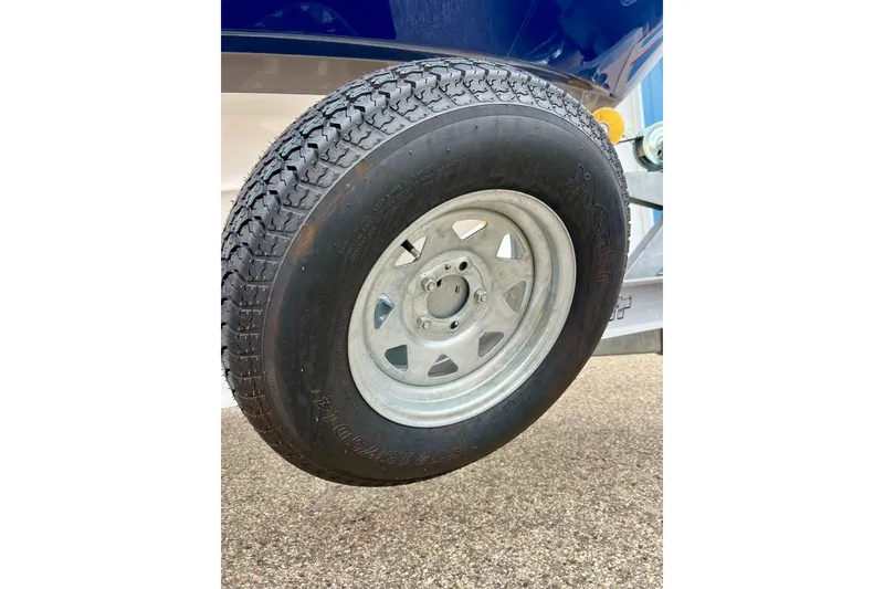Slide: The Image of Close-up of a 2022 Yamaha Boats 255 FSH Sport H trailer tire on pavement. - 6