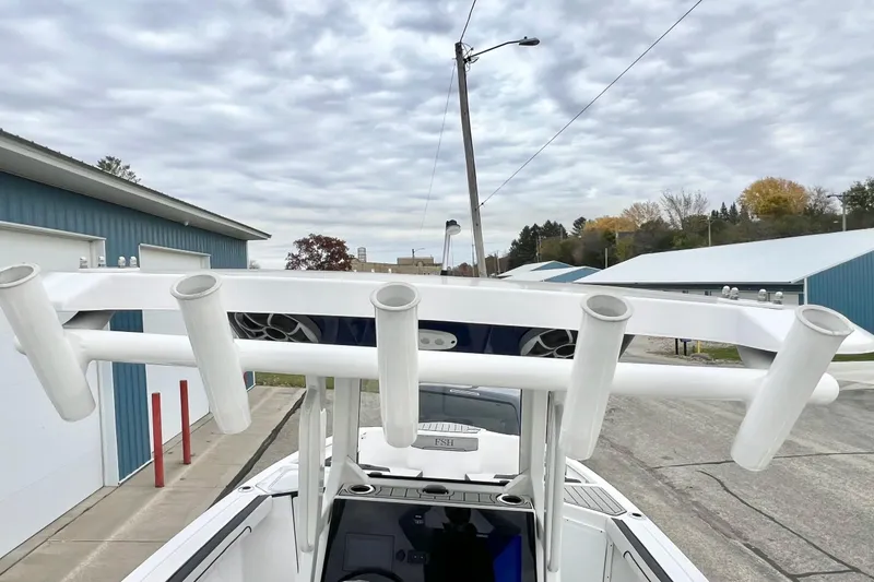 Slide: The Image of 2022 Yamaha Boats 255 FSH Sport H with rod holders and speakers, under cloudy sky. - 79