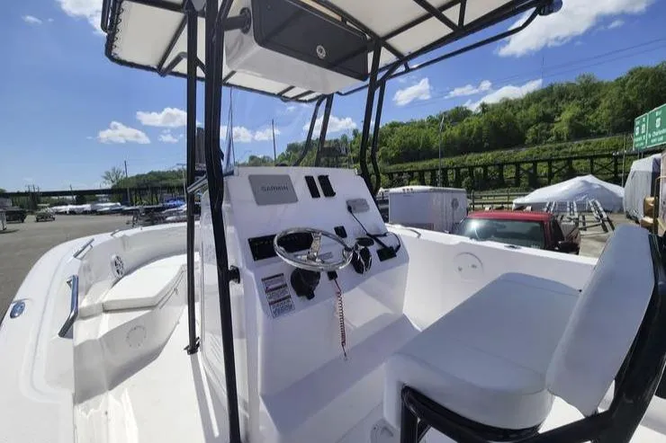 Slide: The Image of 2024 Aquasport 2100 Center Console boat with modern helm and seating, docked outdoors. - 3