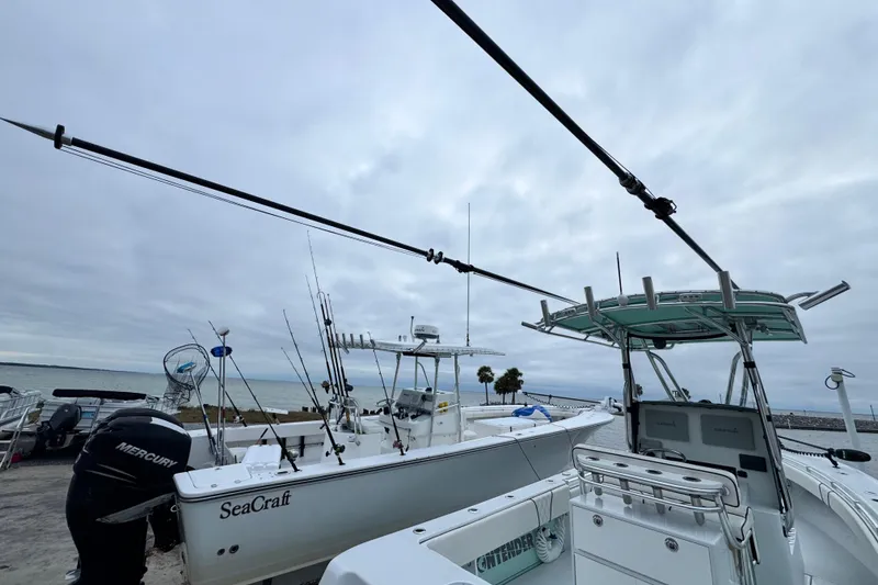 Slide: The Image of 2021 Contender 25 Tournament boat docked beside SeaCraft, with fishing rods and Mercury engine. - 18