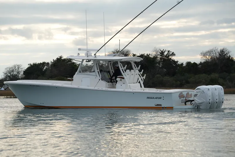 Slide: The Image of 2025 Regulator 37 boat on calm water, featuring triple outboard engines. - 2