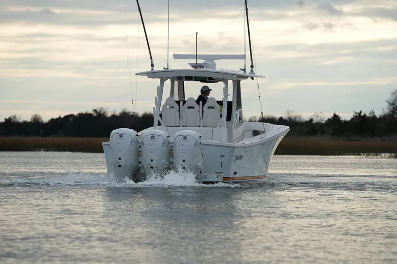 Slide: The Image of 2025 Regulator 37 boat cruising on calm water with triple outboard engines. - 23