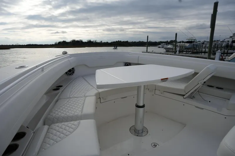 Slide: The Image of 2025 Regulator 37 boat interior with white seating and table, docked by the water. - 79