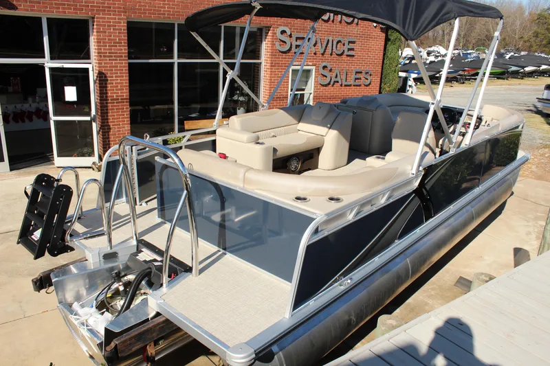 Slide: The Image of 2026 Tahoe Pontoon LTZ Elite boat with canopy, parked outside a sales building. - 3