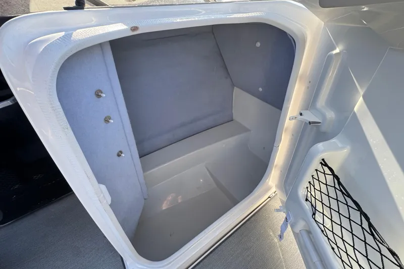 Slide: The Image of 2023 Yamaha AR250 boat storage compartment with netting and secure latch. - 24