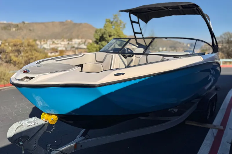 Slide: The Image of 2023 Yamaha Boats AR250, blue and beige, parked on a trailer, scenic background. - 3