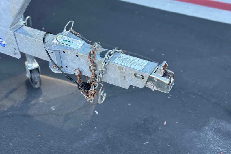 Slide: The Image of Trailer hitch of 2023 Yamaha Boats AR250 with safety chains on asphalt. - 36