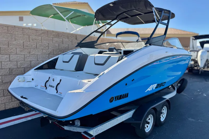 Slide: The Image of 2023 Yamaha Boats AR250 in blue and white on a trailer, parked outdoors. - 5