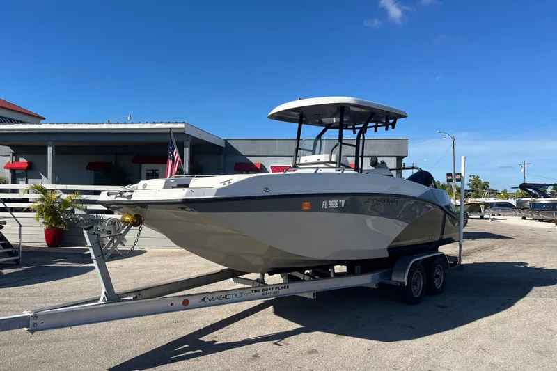 The Image of 2024 Starcraft SVX 231 OB CC boat on trailer, parked outdoors under clear blue sky. - 1