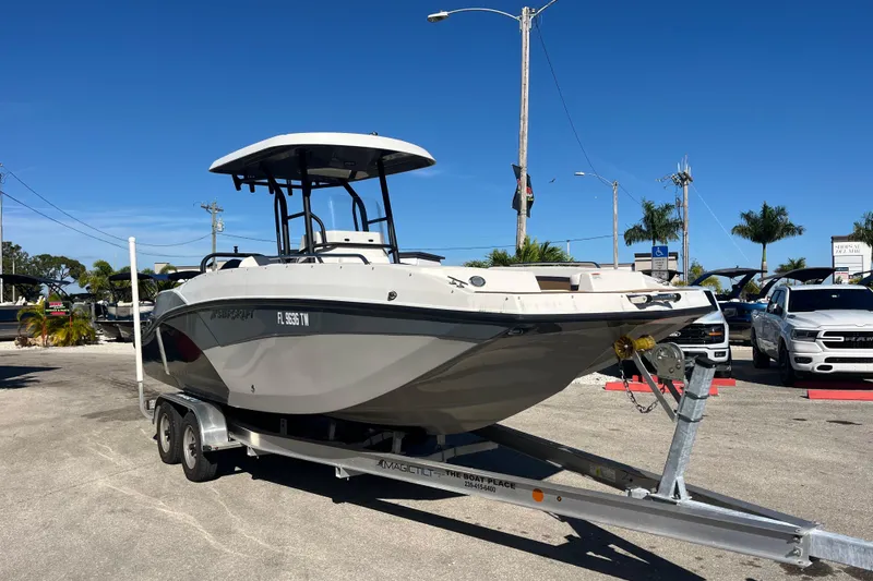 Slide: The Image of 2024 Starcraft SVX 231 OB CC boat on trailer, parked outdoors under clear blue sky. - 2