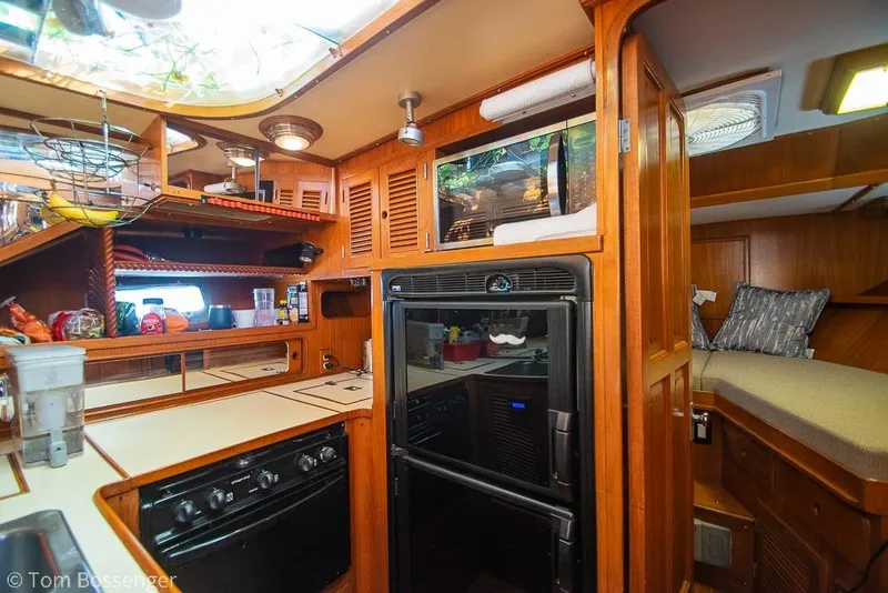 Slide: The Image of Cozy 1985 Spindrift 40 yacht interior with wooden cabinetry and compact kitchen area. - 12